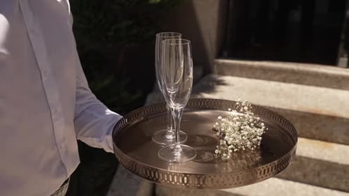 Two Champagne Glasses on a Tray Held by Man