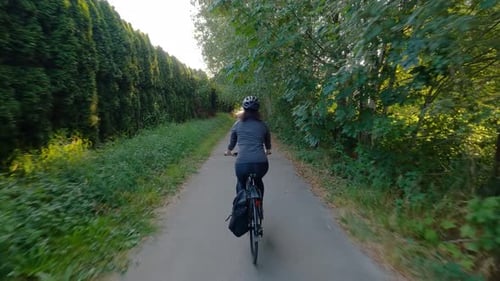 Adventure Woman Bike Riding on a Bicycle Trail Surrounded By Green Trees