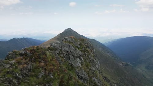 drone flies over a mountain ridge and reveals a big mountain and beautiful landscape in the backgrou