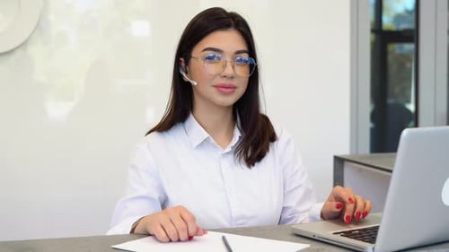 Woman working at desk with laptop and headset