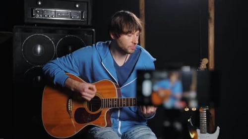 Young Adult Playing Guitar and Recording Himself