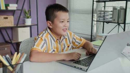 Asian Pupil Studying Online on Laptop in Classroom