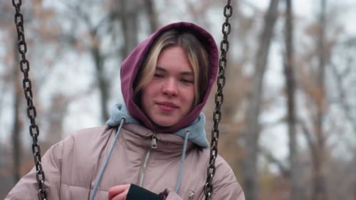 Young Girl Holding Swing Chain and Resting Head in Winter Park