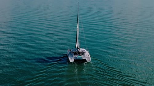 Velero blanco que navega por el mar con un sol brillante en la superficie aérea