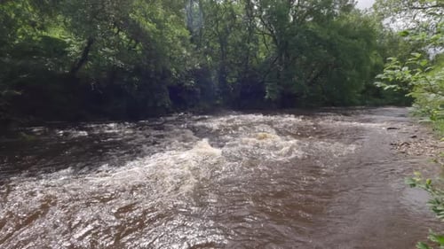 statische Aufnahme, die einen überfluteten Fluss zeigt, der gefährlich schnelle Strömungen erzeugt