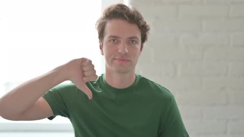 Joven molesto mostrando los pulgares hacia abajo