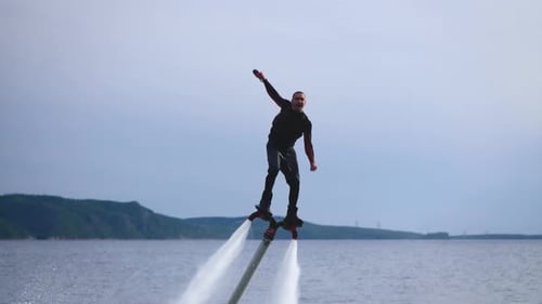 El flyboard, un nuevo deporte extremo Un hombre, un flyboarder, realiza volteretas sobre el agua Un ágil y entrenado