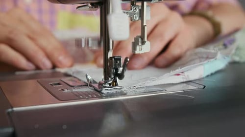Mains d'une couturière cousant ensemble un tissu sur une machine à coudre