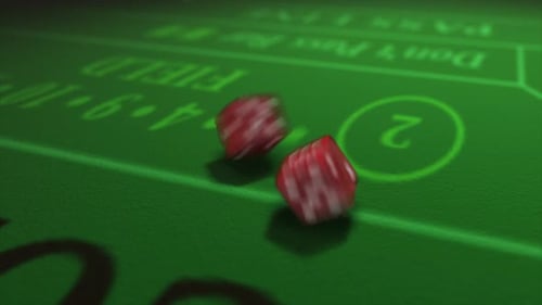 Pair of dice thrown onto a craps or crapaud table with glittering poker machines in a casino backgro