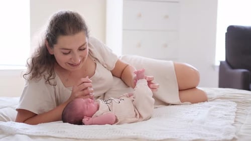Mother Bonding with Newborn Infant on Bed Indoors