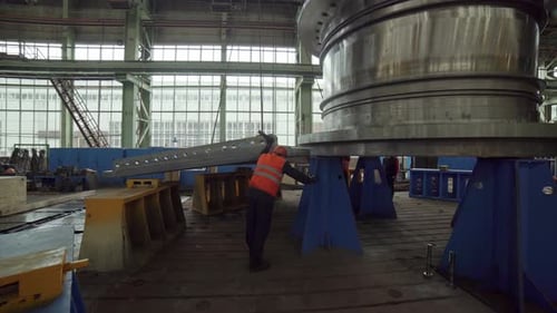 An Industrial Worker Actively Handling a Large Machinery Component Inside a Factory Environment