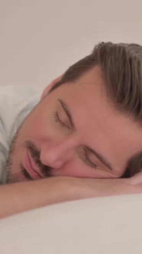 Junger Mann schläft, während er im Bett auf dem Bauch liegt, vertikales Video