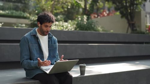 Portrait of Happy Hispanic Man Freelancer Joins Video Call Via Laptop in Park