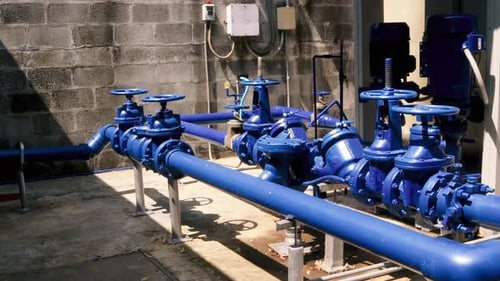 An establishing shot of a blue industrial irrigation system, a series of pressure valves and pumps e