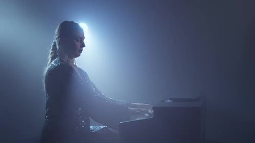 Woman Plays Piano in Dramatic Lighting