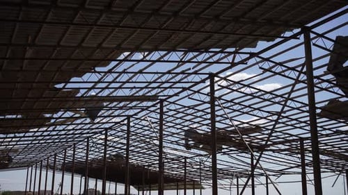 Damaged Roof Frame with Torn Metal Sheets and Rusty Beams Abandoned Building Concept