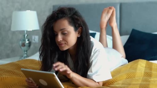 Woman Using Tablet While Relaxing on Bed
