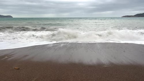 A Strong Sea Wave Washes the Resort Beach in Cloudy Weather