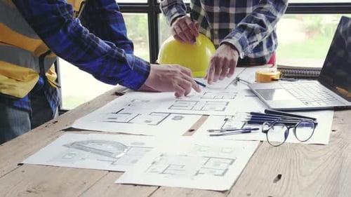 Architects Reviewing Blueprints on Wooden Table Indoors