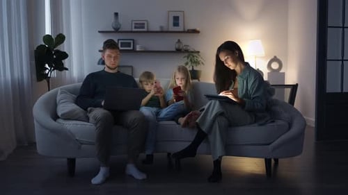 Family Relaxing Together on Couch with Electronic Devices