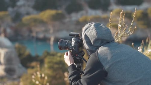 Man Adjusting Camera for Ocean and Nature Photography