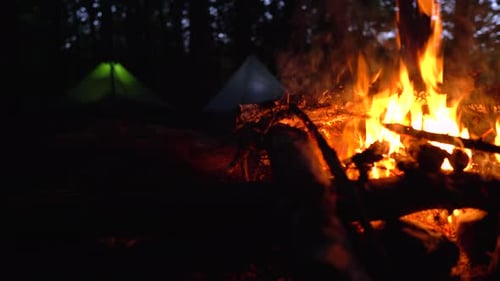 Slider dolly close up of campfire and glowing tents in the background