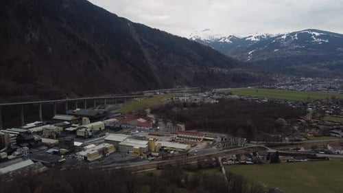 Révélation aérienne d'une zone industrielle, d'une autoroute et d'une voie ferrée dans les montagnes par temps nuageux.