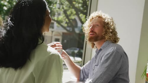 Happy diverse couple drinking coffee and talking in cafe