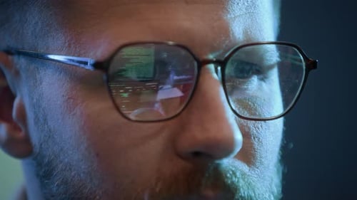 Männlicher Hacker mit Brille codiert am Computer drinnen, Nahaufnahme