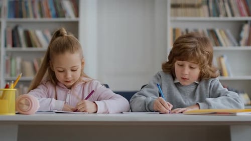 Children Writing at Desk in School Library