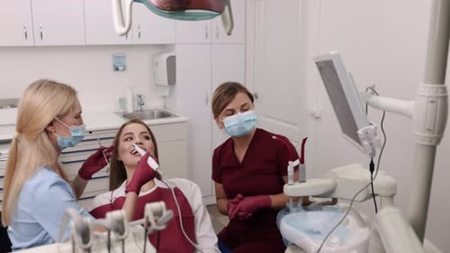 Dentist Examining Patient with Assistant in Modern Clinic