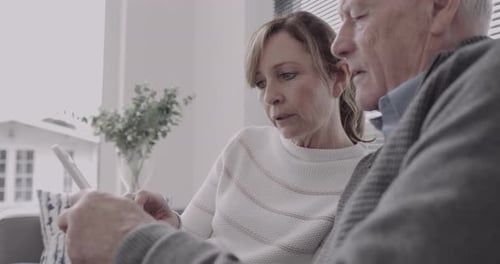 Loving Senior Couple Looks at Tablet Together Indoors