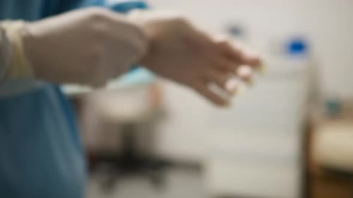 Surgeon Puts On Sterile Gloves in Hospital Room