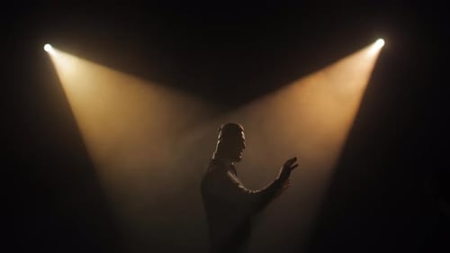 Artist Singing and Gesturing While Standing on Bright Stage