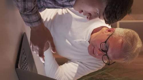 Teen Teaching Senior Man How to Use a Laptop