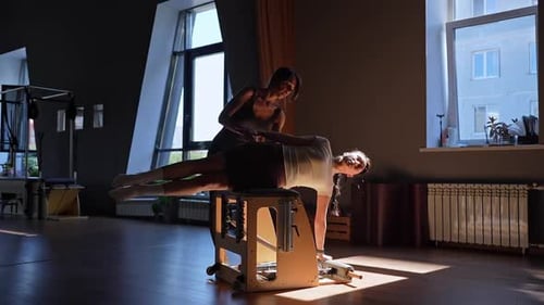 Woman Doing Pilates on Machine with Instructor