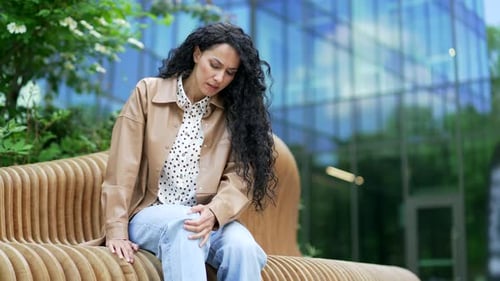 Woman Massaging Sore Knee on Bench Outdoors
