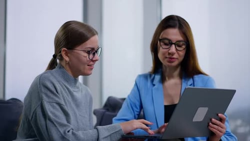 Two Women Collaborate at Work With Laptop