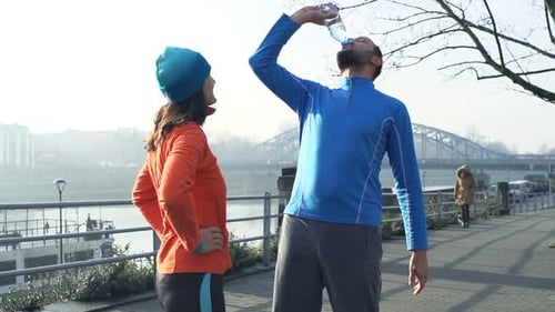 Couple Talking and Drinking Water After Jogging in City, Super