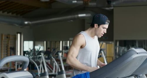 A guy in the gym to stay fit and have defined muscles or lose weight runs on the treadmill with a