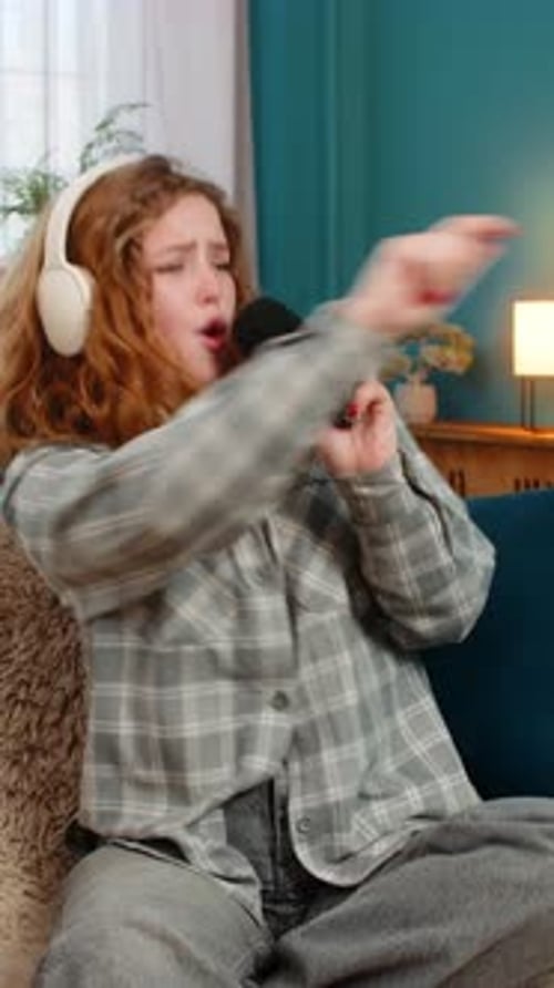 Enthusiastic young woman singing into a microphone at home