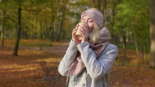 Attractive Lady Standing in Park Enjoying Nice Weather and Coffee