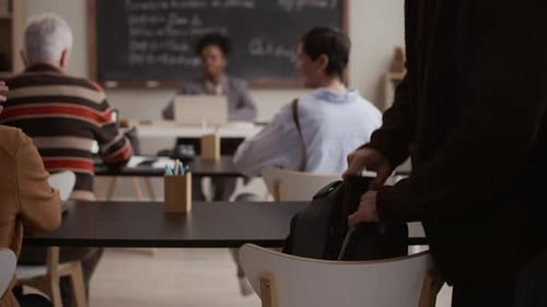 Adults Gather with Laptops at Tables in Classroom