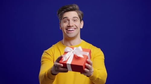 Smiling Man Offers Gift on Blue Background