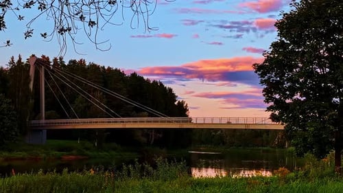 Suspension bridge over Gauja River during colorful summer sunset