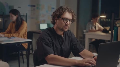 Young Man Posing on Camera at Office Workplace during Night