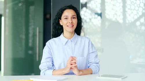 Webcam view. Young female employee talking on a video call looking at camera sitting at workplace