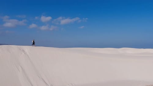 A Solitary Figure Traverses a Vast White Sand Dune Under a Clear Blue Sky on Socotra Island