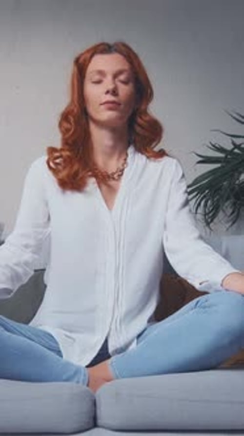 Red-Haired Woman Meditating Calmly on Couch