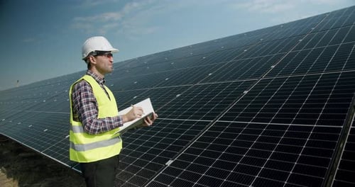 Positiver erwachsener Mann in Uniform überprüft Photovoltaikmodule